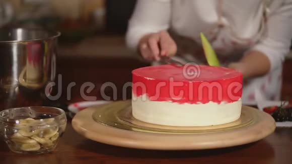 将旋转在木制托盘上的蛋糕特写镜头厨师为甜点上色视频的预览图
