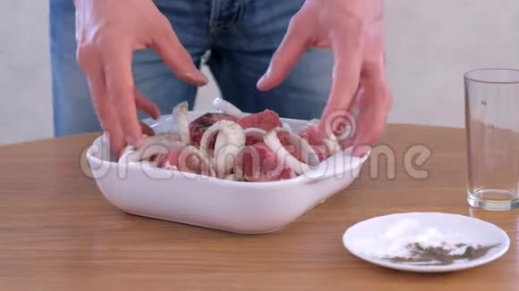 一个男人把猪肉块和洋葱和香料混合在一起腌制沙什利克视频的预览图