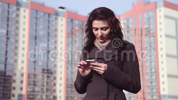 一个女孩在高楼的背景下用电话视频的预览图