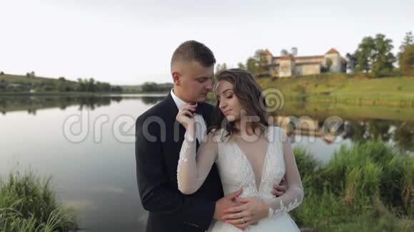 白人新郎和新娘在湖边的公园里新婚夫妇新婚夫妇接吻视频的预览图