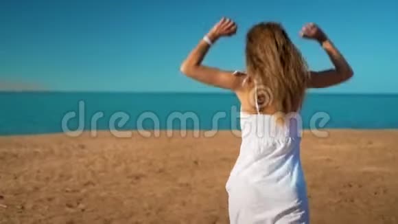 穿着白色裙子的快乐女孩奔向大海欢欣鼓舞视频的预览图