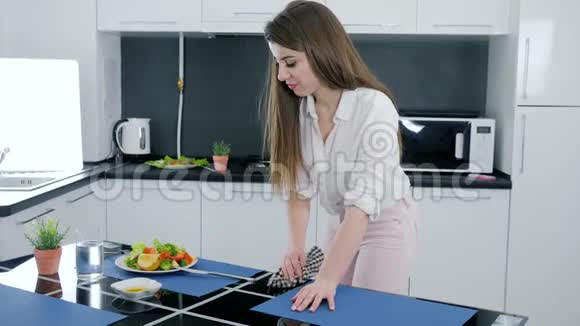 年轻女子在家做完沙拉后从厨房的桌子上打扫卫生视频的预览图