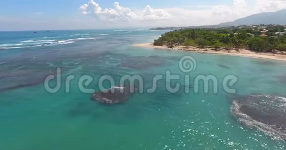 飞越美丽的海浪到异国情调的海岸线与房屋和棕榈4k顶部视图视频的预览图