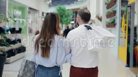一对拎着包走过商场的夫妇视频的预览图