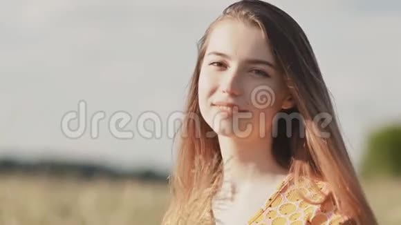 年轻漂亮的女孩穿着夏装长发在草地上女孩特写的脸女孩正在整理她视频的预览图