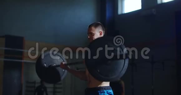 强壮的赤膊运动员在阳光明媚的健身房里举起杠铃视频的预览图
