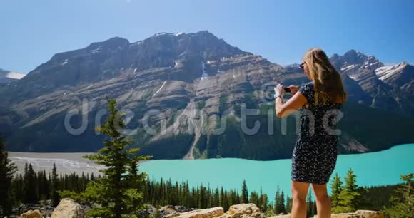 女人用手机点击照片站在岩石上4k视频的预览图