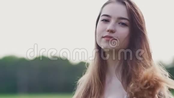 美丽的年轻女孩长发在相机上摆着自然背景和森林女孩特写的脸这就是视频的预览图