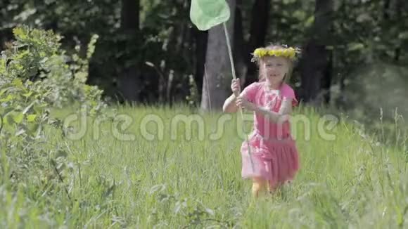 一个蝴蝶网穿过林间空地的孩子头上戴着蒲公英花圈视频的预览图