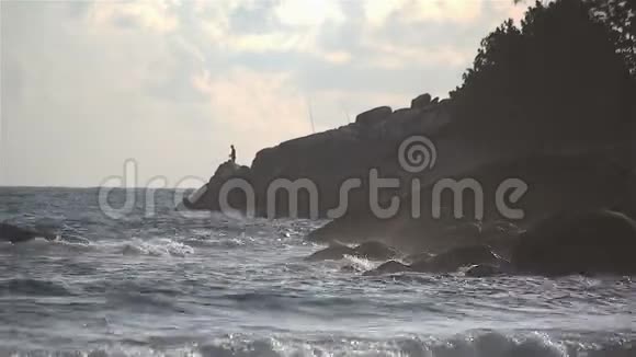 日落时海浪拍打海岸岩石背景是渔夫视频的预览图