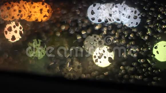 夜晚灯光下玻璃上的雨滴视频的预览图