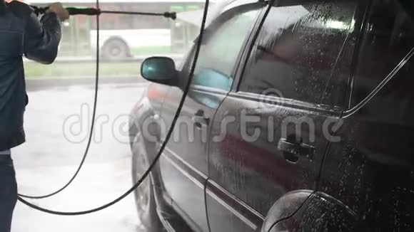 一个人洗了一辆黑色的车自助洗车过程中的慢动作视频用水喷射视频的预览图