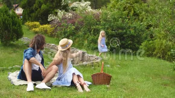 幸福的家庭和他们可爱的女儿蓝色的衣服戴帽子的女人在户外野餐视频的预览图