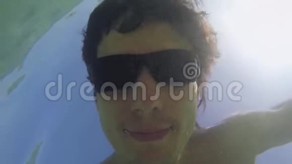 在阳光明媚的夏日年轻人戴着太阳镜在蔚蓝的海洋里水下游泳慢动作1920x1080视频的预览图