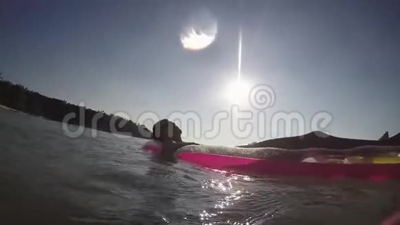 年轻的游客在充气床垫上放松在镜头耀斑效果上泼水在海上晒太阳视频的预览图