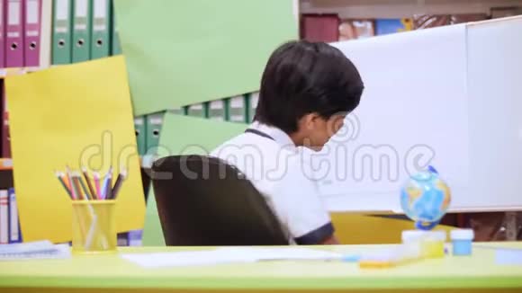 一个男孩躺在椅子上拿起一支铅笔在笔记本上写一些东西视频的预览图