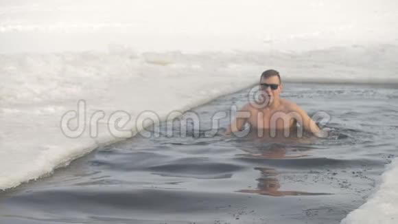 一个戴墨镜的人在冰冻的水里鸭子视频的预览图