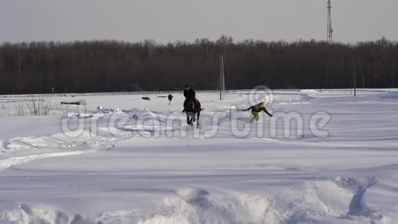 慢动作一个女孩在马上疾驰一匹马正用绳子拖着一个滑雪者一个滑雪者骑在船上视频的预览图