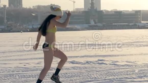 一个女人在冬天穿着泳衣跑步时摘下帽子视频的预览图