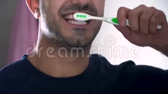 男人在浴室的镜子前刷牙一个年轻人在镜子里的倒影一种平静和疲惫视频的预览图