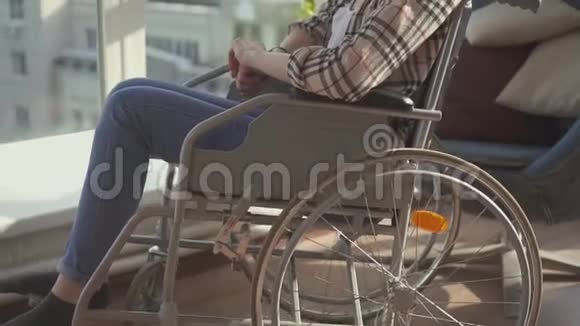 坐在轮椅上靠窗的残疾女孩慢节奏视频的预览图