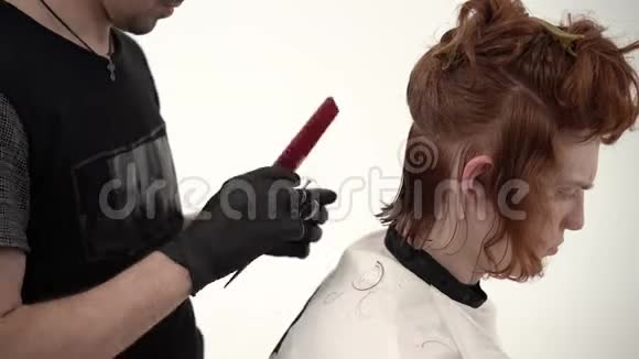 理发师大师给一个留着红色长发的年轻人理发视频的预览图
