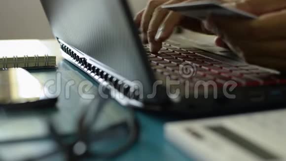 手持信用卡和输入笔记本电脑键盘进行在线支付的人的手视频的预览图