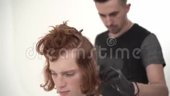 理发师大师给一个留着红色长发的年轻人理发视频的预览图