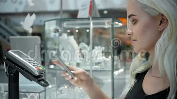 女士金发时尚模特在超市用手机支付NFC技术视频的预览图