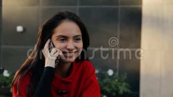 年轻的商务女士坐在街上一家咖啡馆的桌子旁用手机说话视频的预览图