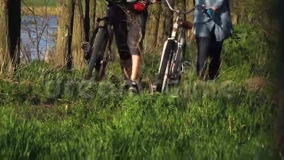 一男一女骑着自行车在河边的树林里散步视频的预览图