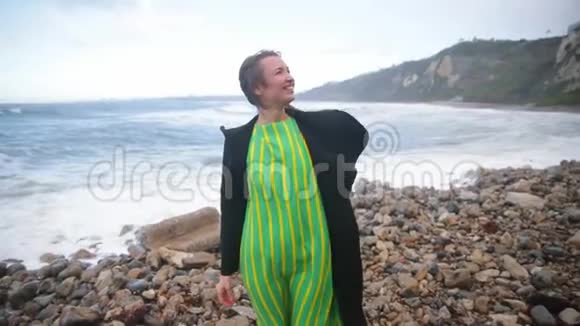 动机射击幸福的女人站在海边仰望天空寒冷的阴天风的天气视频的预览图