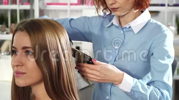 与她的女客户合作用卷发熨斗为女性发型师做特写视频的预览图