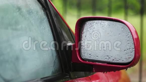 特写车上的玻璃窗上滴下的雨滴滴下了许多溪流雨滴在侧面的镜子上视频的预览图