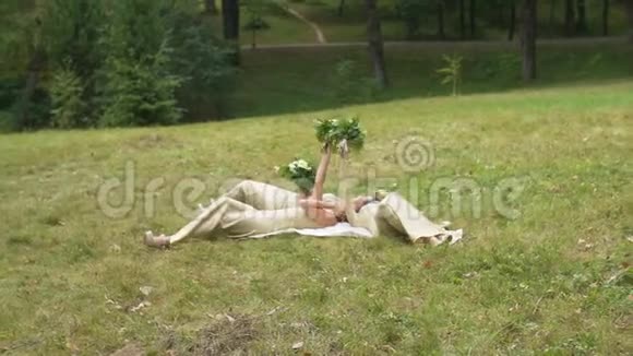 三个年轻漂亮的伴娘穿着长裙躺在绿色的草地上捧着白色的花束视频的预览图