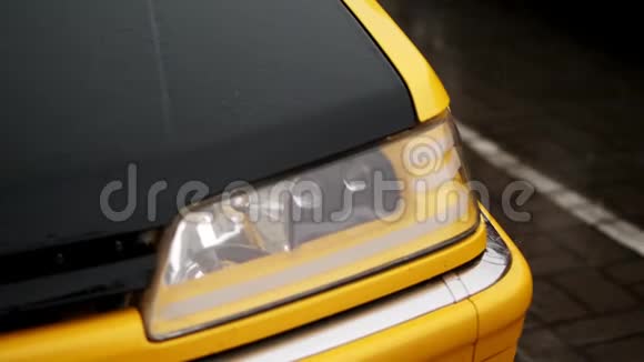 关门汽车前照灯淋浴时大量的水滴溅落在黑色和黄色汽车罩的潮湿表面视频的预览图