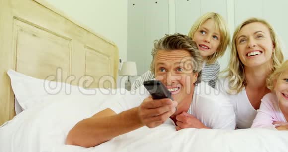 幸福的一家人在床上看电视视频的预览图