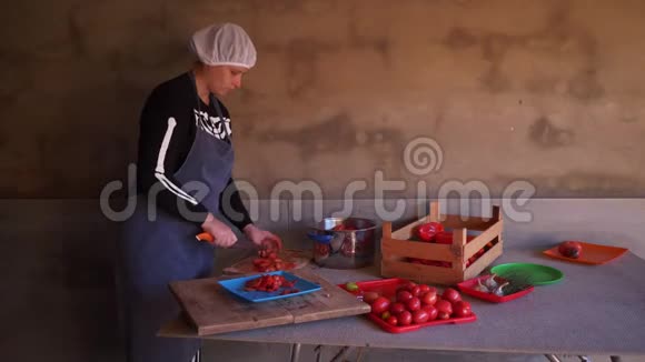 年轻的女厨师穿着骷髅服装围裙切红番茄做番茄酱视频的预览图