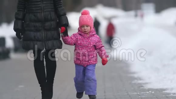 可爱的小女孩和她的母亲在冬天的街道上散步女儿闯出去独立出去视频的预览图