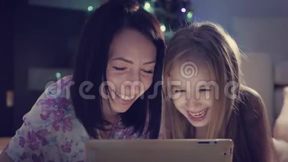 一家人的母亲和女儿在躺在地上数字平板电脑上的礼物圣诞节视频的预览图