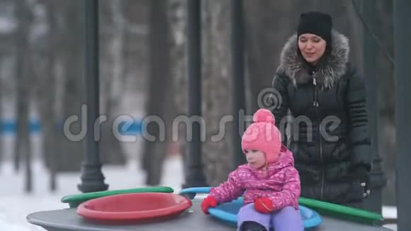 妈妈和可爱的小女儿一起在冬季公园玩耍视频的预览图