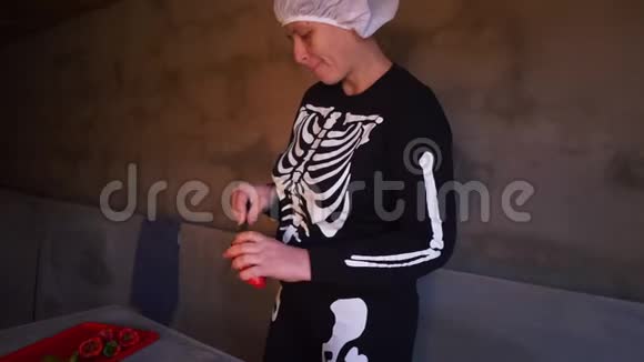 年轻的女厨师穿着骷髅服装围裙切红番茄做番茄酱视频的预览图