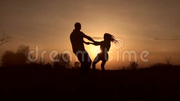 日落时分一对情侣在草地上旋转视频的预览图