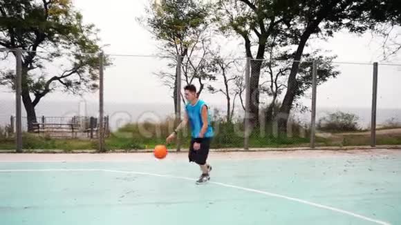 年轻人成功地在公园球场上投掷篮球慢动作射击视频的预览图