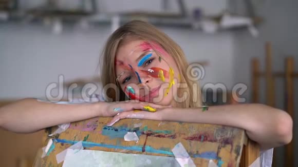 一位年轻迷人的艺术家的肖像她的脸上有油漆靠在画架上视频的预览图