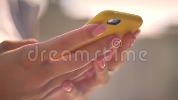 夏季阳光明媚的一天女人在智能手机上打字的双手交流观念模糊的背景侧视视频的预览图