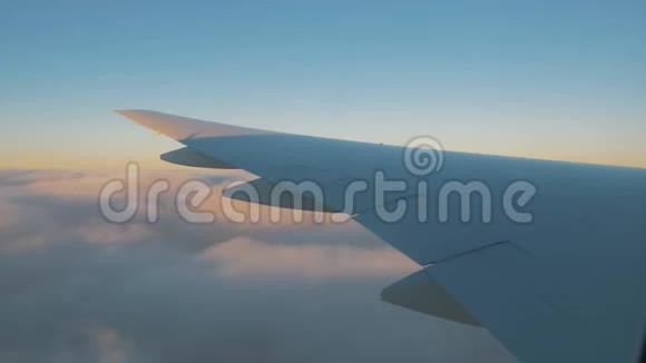 飞机飞行一架飞机的机翼在云层上方飞行天空是夕阳从飞机的窗口看视频的预览图