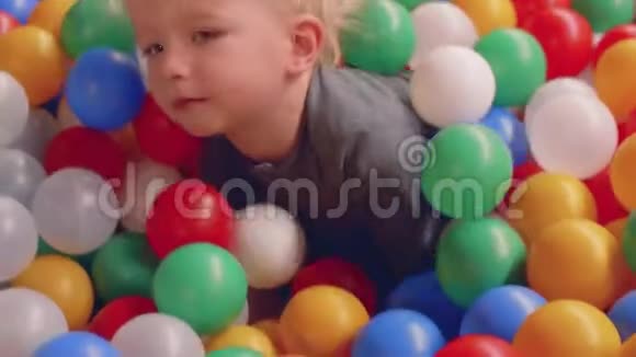 金发的蹒跚学步的孩子试图摆脱大量的小球并得到他母亲帮助视频的预览图