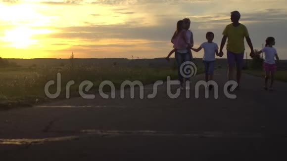 幸福的爸爸和妈妈带着三个孩子在日落时在农村上路幸福的家庭在大自然中玩得很开心旅费视频的预览图