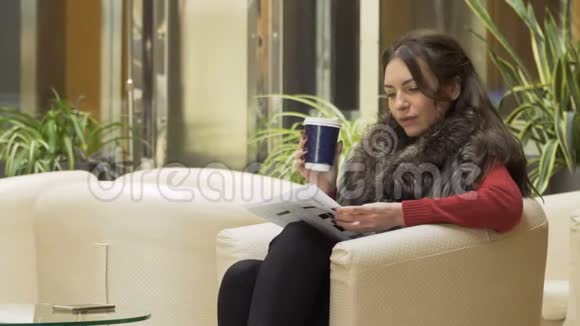 时尚女性在酒店大堂喝咖啡翻阅文件视频的预览图
